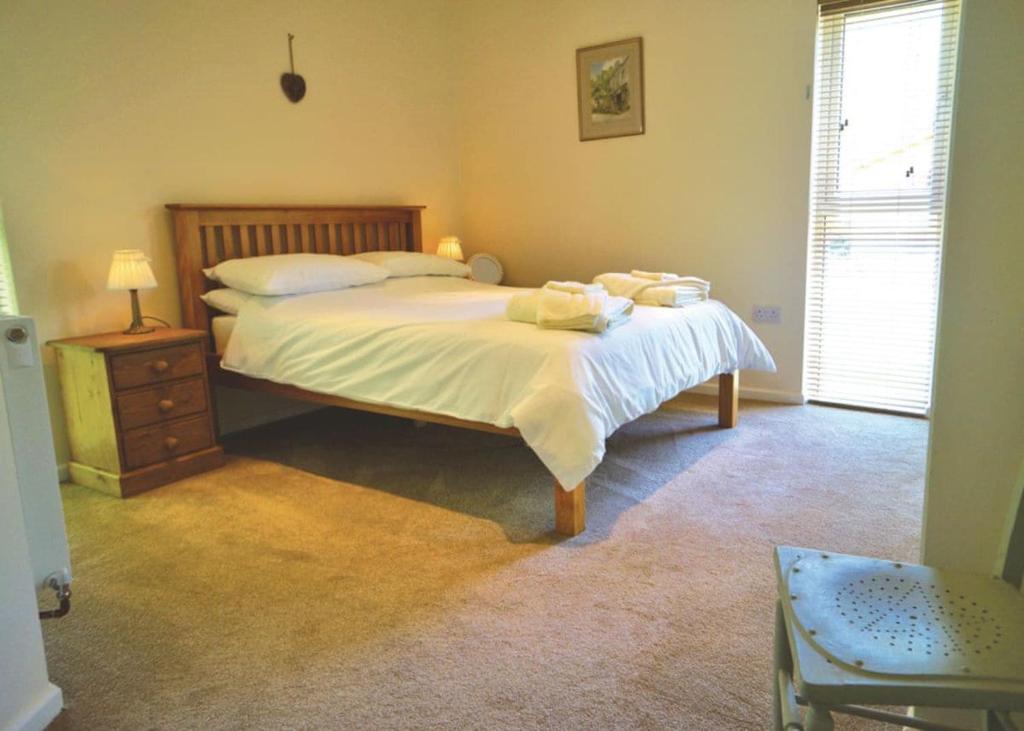 een slaapkamer met een bed met witte lakens en een nachtkastje bij Clun Valley Lodges in Clunton