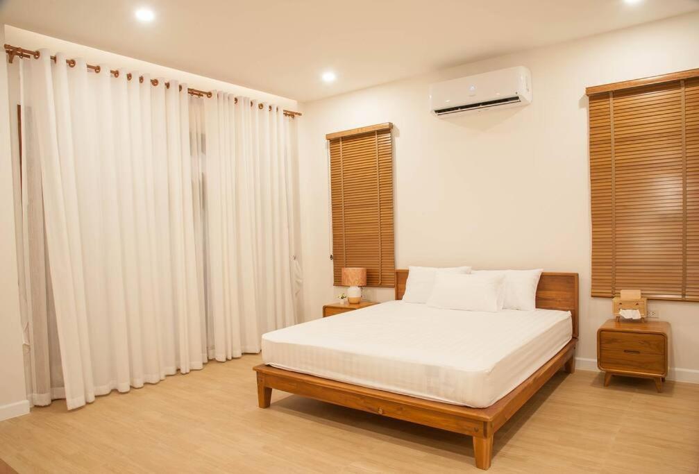 1 dormitorio con 1 cama con sábanas blancas y ventanas en Chao Sam Ran Pool Villa Phetchaburi หาดเจ้าสำราญ เพชรบุรี ราคาสำหรับ 8 ท่าน, en Haad Chao Samran