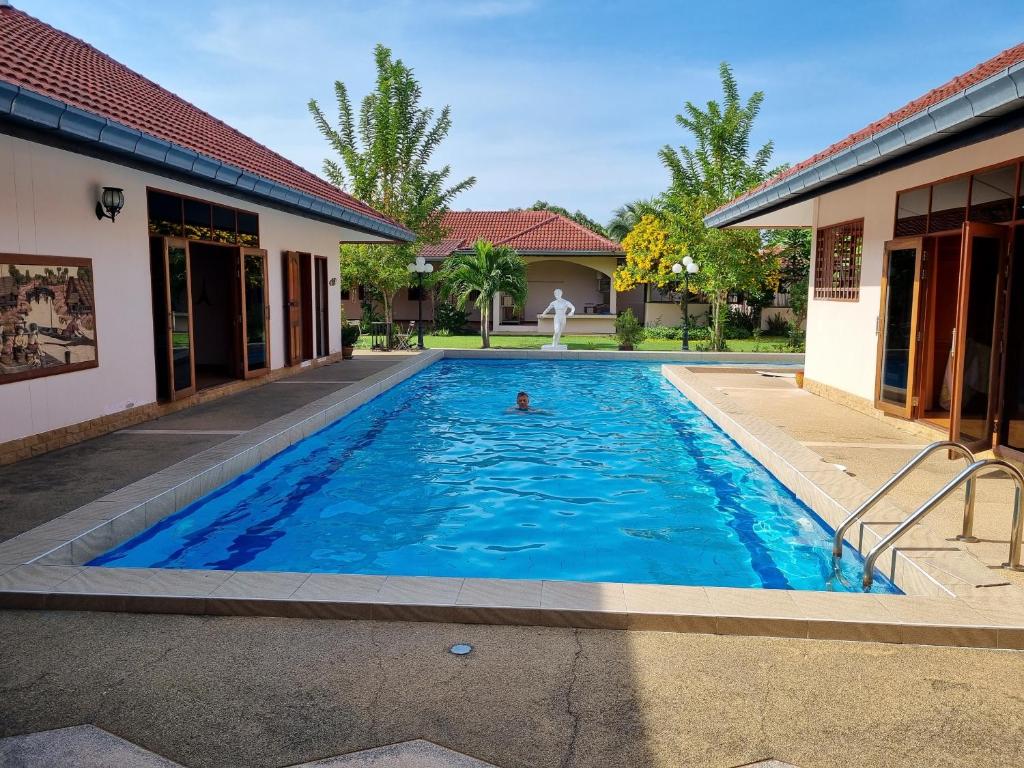 a person swimming in a swimming pool next to a house at Meyers Hua Hin in Hua Hin