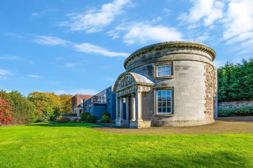 una vieja casa redonda en un campo de hierba en Craigiehall Temple, en Edimburgo