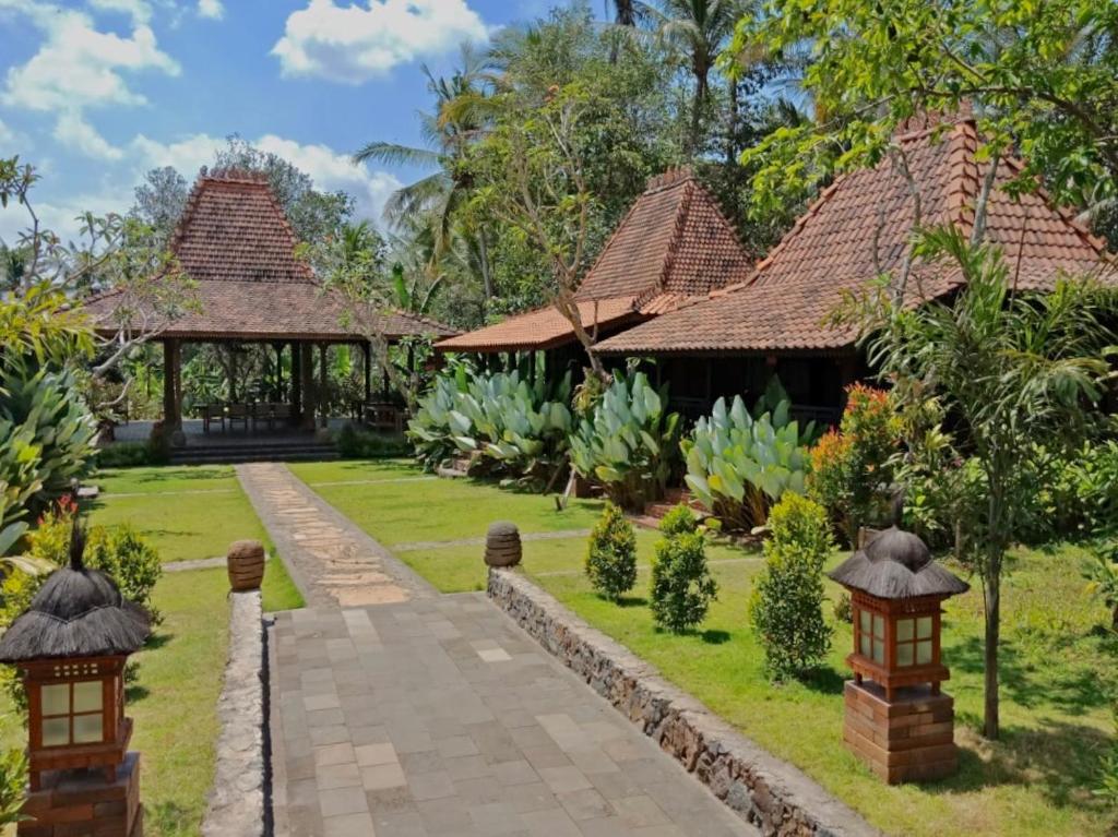 a garden of a house with a pathway and a pavilion at Alas Arum Ecolodge in Tabanan