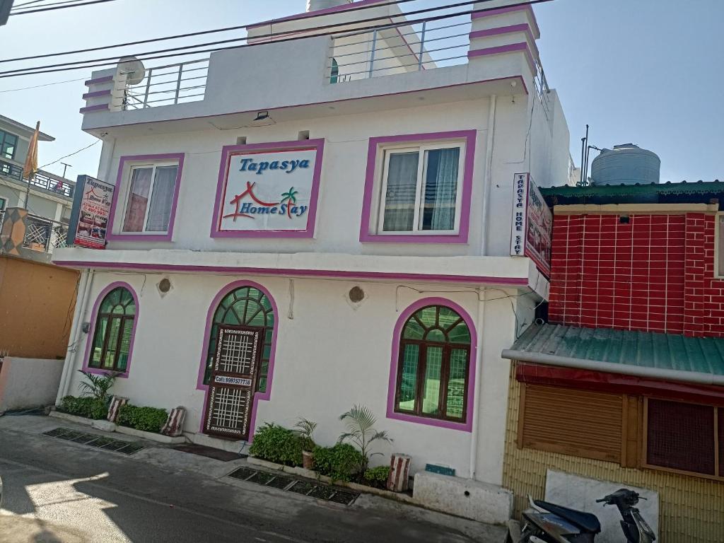 un bâtiment rose et blanc avec un panneau sur celui-ci dans l'établissement Tapasya Home Stay, à Dehradun