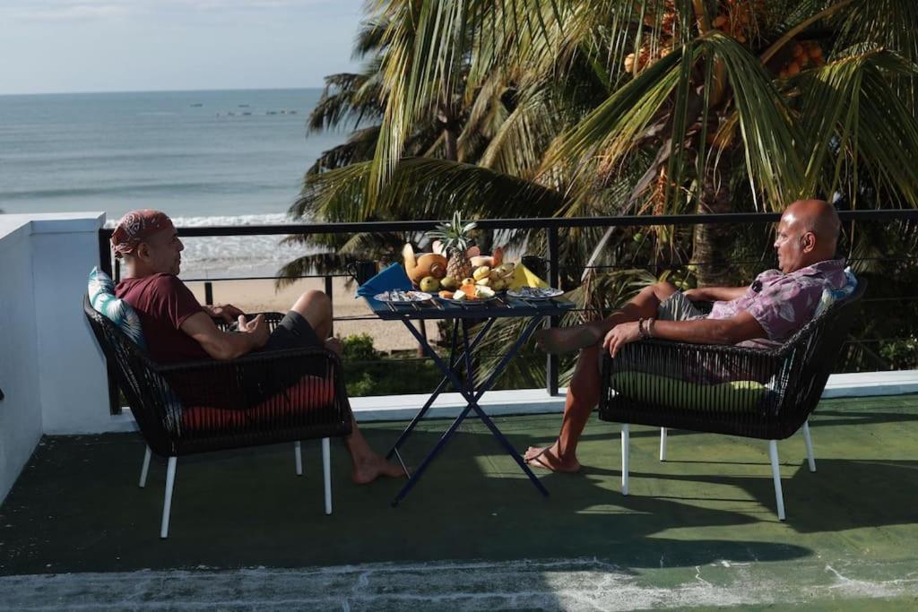 2 hommes assis sur des chaises sur un balcon avec vue sur la plage dans l'établissement Yachtmans House, à Matara