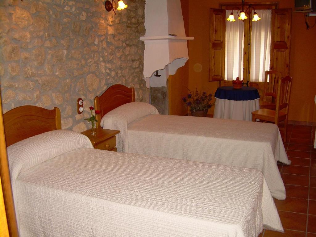 drie bedden in een kamer met een stenen muur bij Casa Rural el Castellet in La Jana