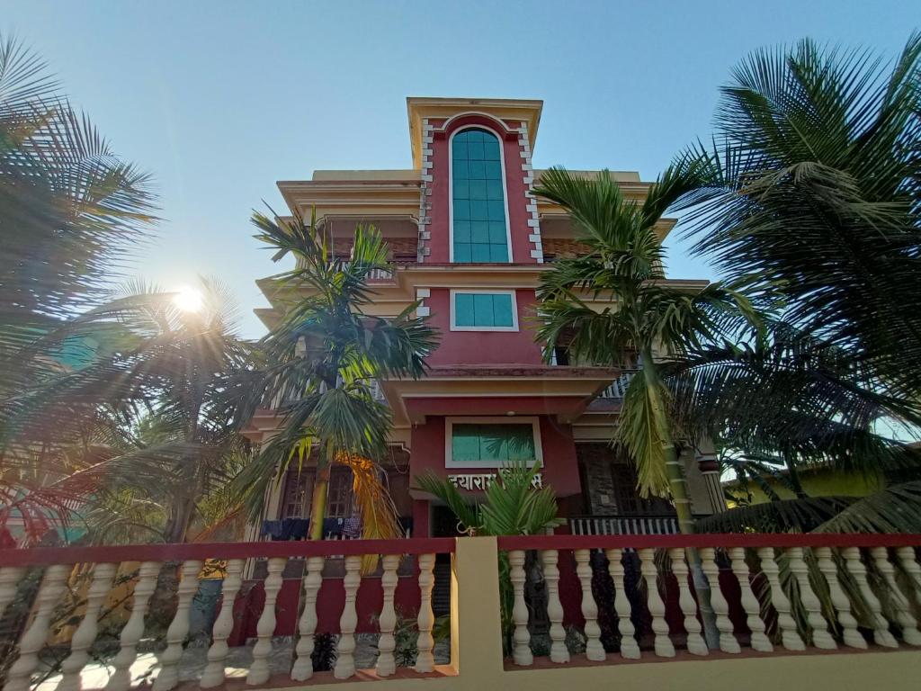 a pink house with palm trees in front of it at Pappa's Guest House in Arambol