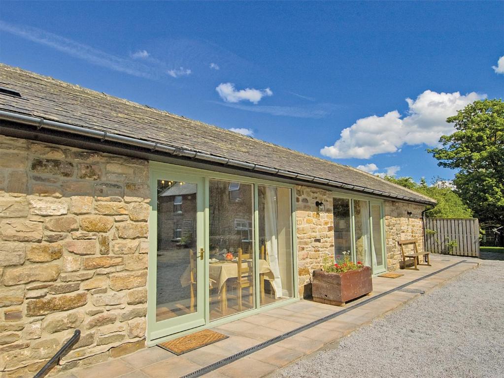 uma casa de pedra com portas de vidro deslizantes e um pátio em Lapwing Cottage - E5028 em Birtley