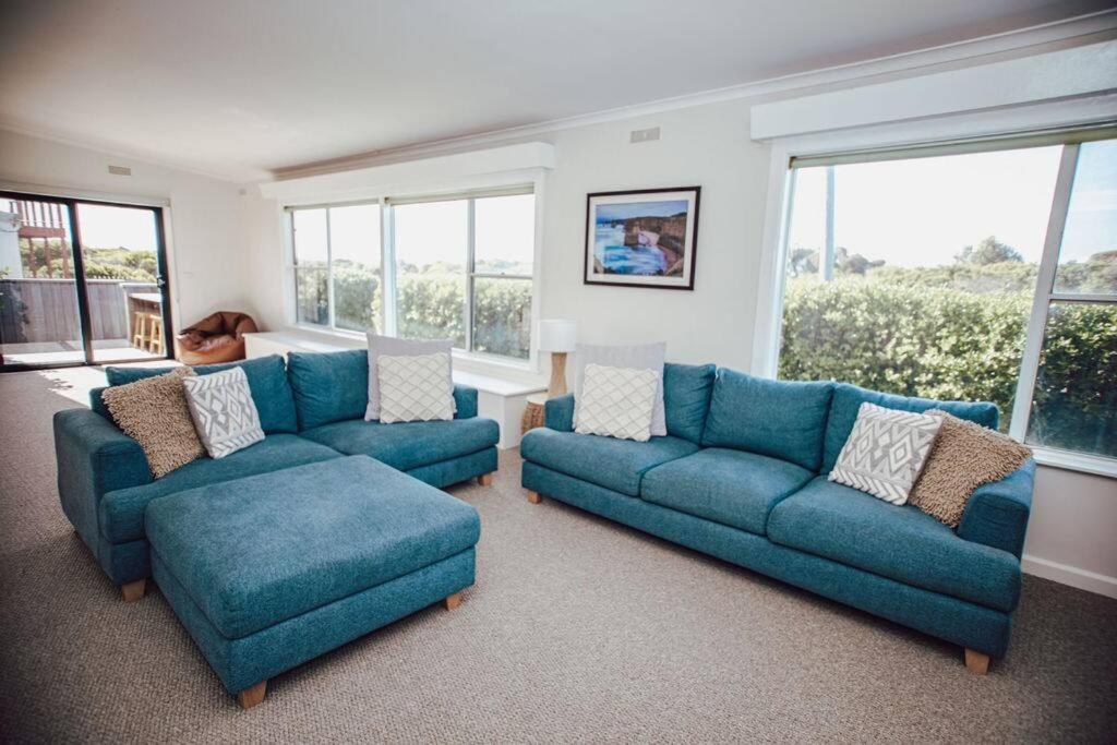 a living room with two blue couches and windows at Ocean Blue in Peterborough