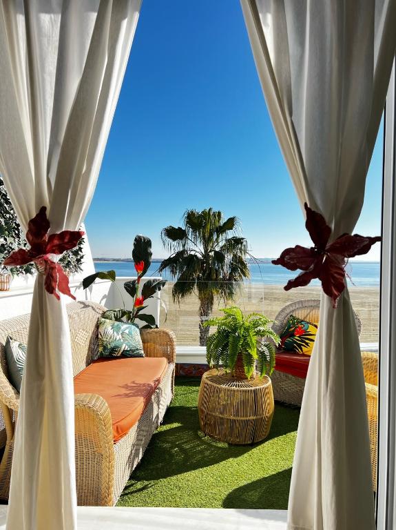 a window with curtains and a view of the beach at Ático Good Vibes in Rota