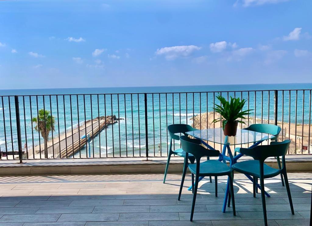 a table and chairs on a balcony with a view of a beach at Beach Place Apartments in Haifa