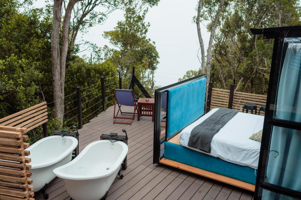 a bedroom and a bed on a deck with a tub and sinks at The Stargazing Cube - Misty Mountain Reserve in Stormsrivier
