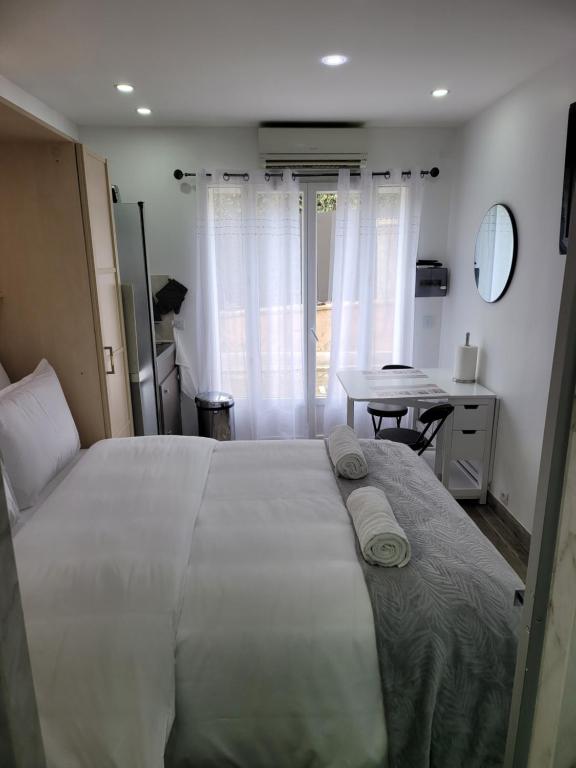a bedroom with a large bed and a table at Studio 1 à La Trinité proche de Nice, Monaco et l'Italie in La Trinité