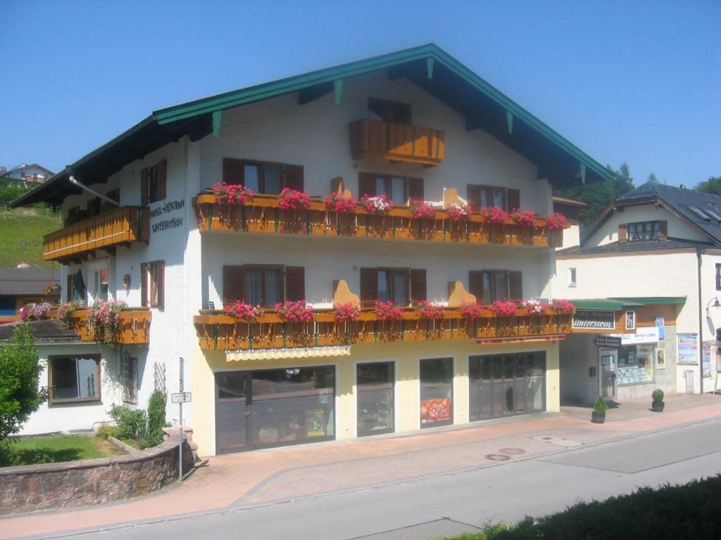 ein großes weißes Gebäude mit Blumen auf den Balkonen in der Unterkunft Pension Unterstein in Schönau am Königssee