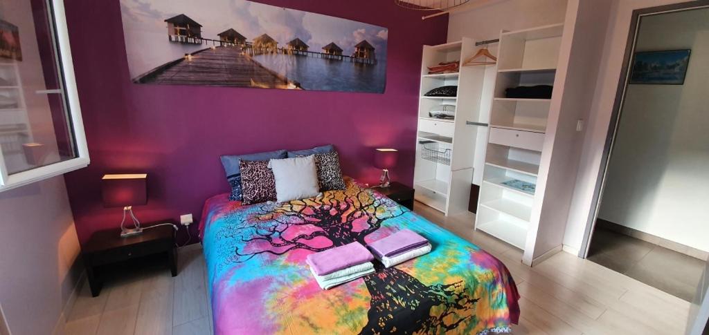 a bedroom with a colorful bed and a purple wall at 1 Chambre privative avec bureau et cuisine dans maison 105 m2 Montfaucon in Montfaucon