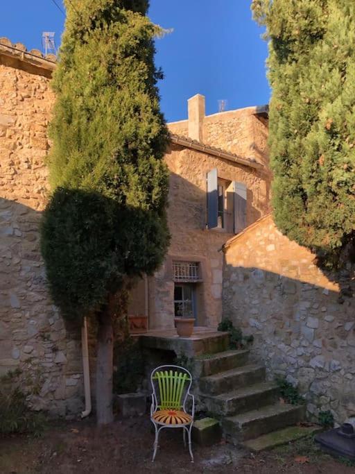 une chaise verte installée à côté d'un bâtiment en pierre avec des escaliers dans l'établissement Maison de caractère au coeur de la Provence, à Robion
