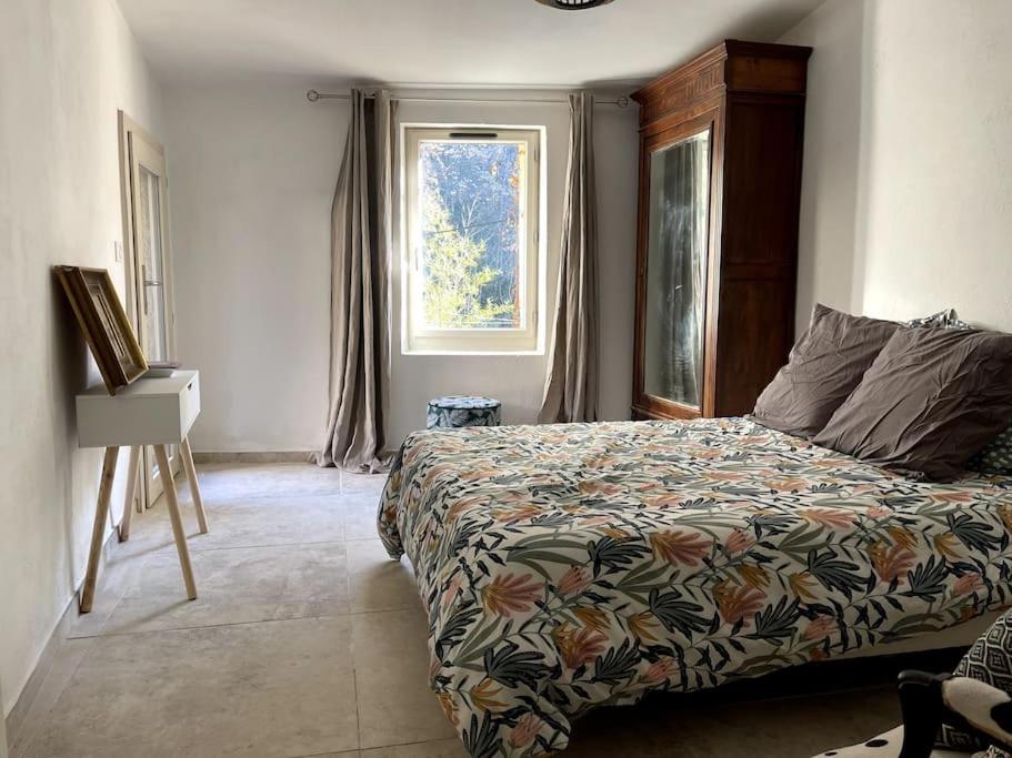 een slaapkamer met een bed en een raam bij Maison de caractère au coeur de la Provence in Robion en Luberon