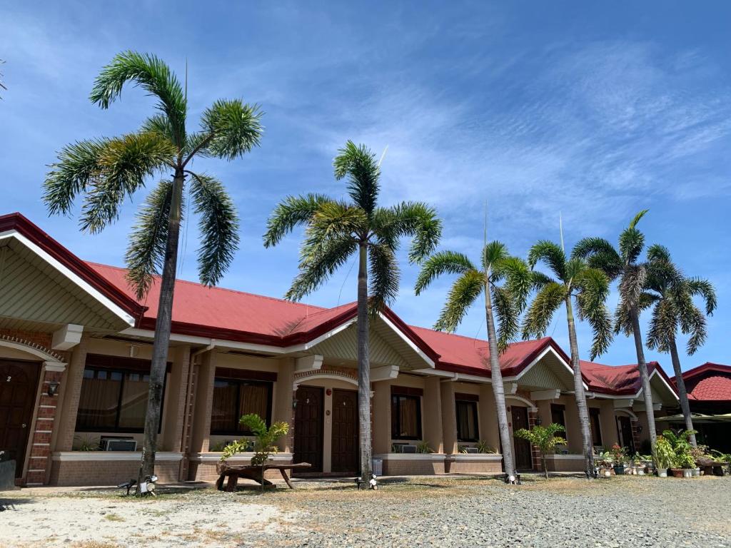 a building with palm trees in front of it at Balay Inato Pension in Puerto Princesa City