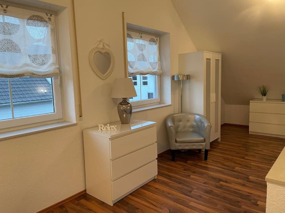 um quarto com uma cómoda, uma cadeira e janelas em Melli‘s Seenahe Ferienwohnung em Langenargen