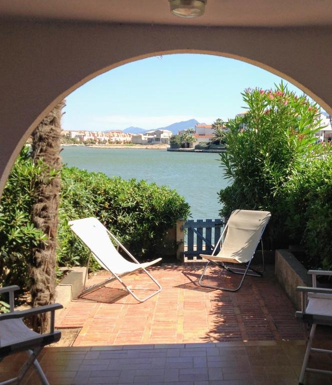 - deux chaises assises sur une terrasse avec vue sur l'eau dans l'établissement Marina sur presqu’île des Capellans (Wifi) 6 couchages, à Saint-Cyprien