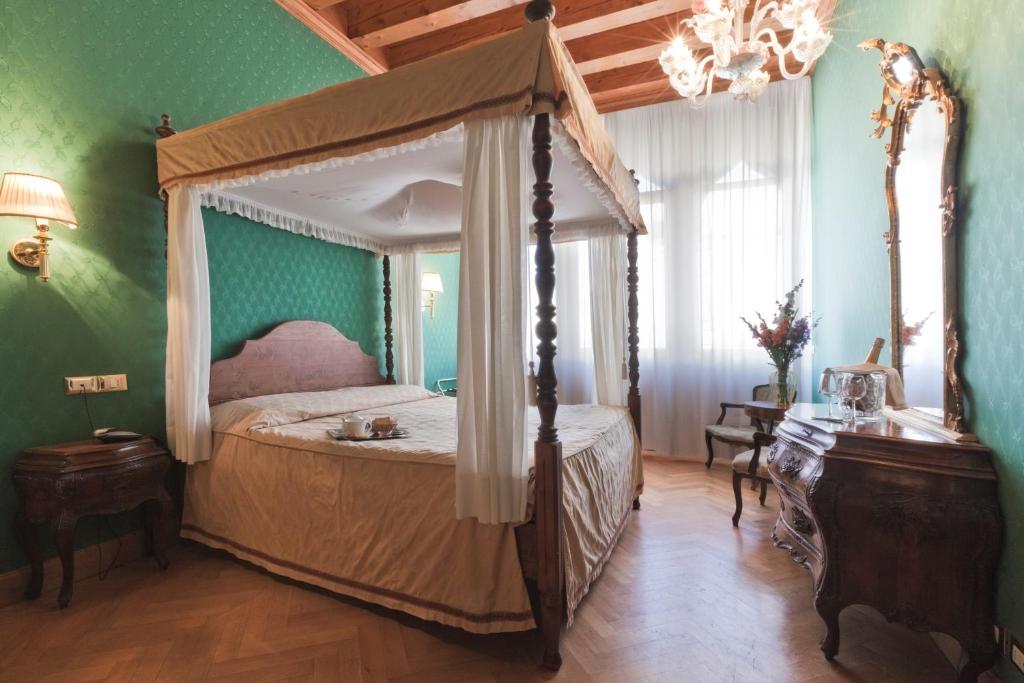 a bedroom with a canopy bed and green walls at Palazzo Cendon Piano Antico in Venice