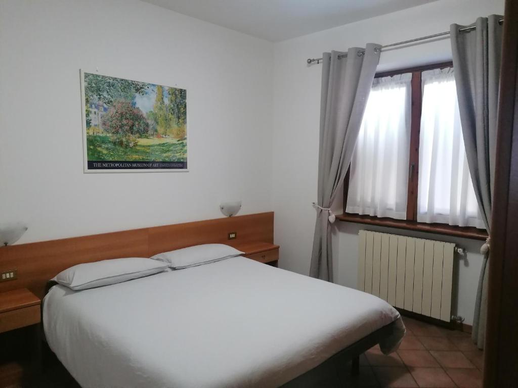a bedroom with a white bed and a window at Sweet Home Casa Vacanze "Il Bilocale" in Songavazzo