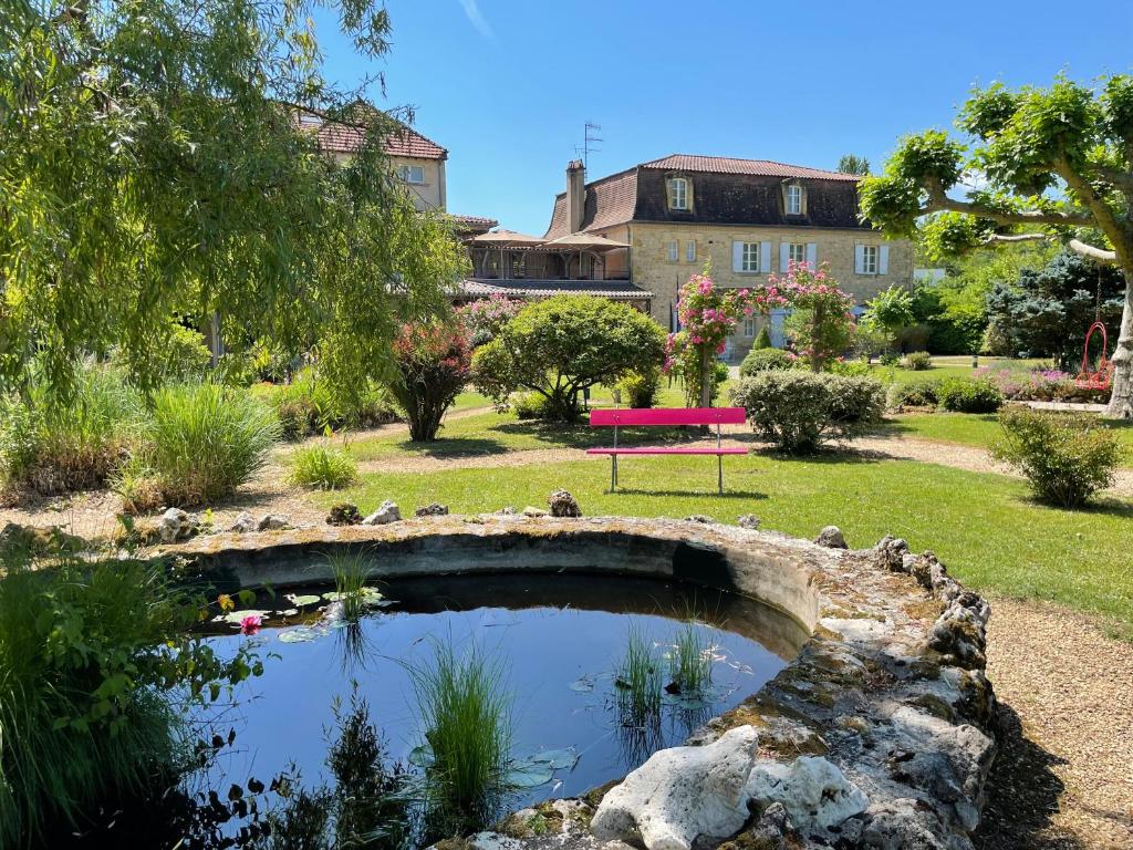 un pont sur un étang dans un jardin dans l'établissement Les Glycines - Hôtel & Spa - Teritoria, à Les Eyzies-de-Tayac