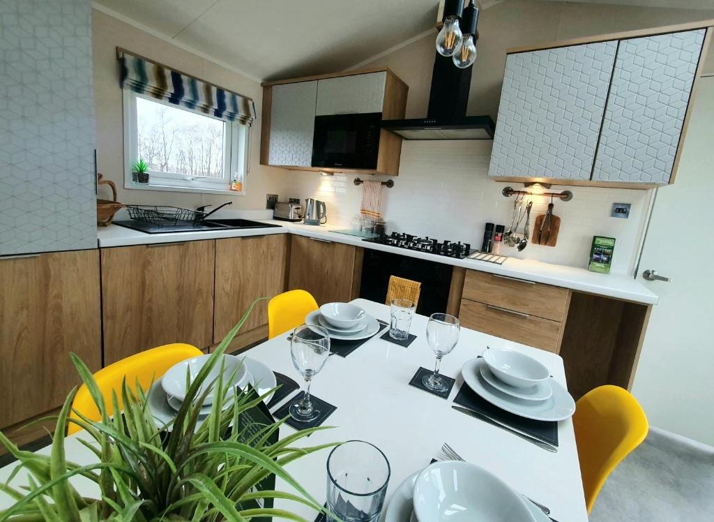 a kitchen with a white table and yellow chairs at View point lodge in Newton on the Moor