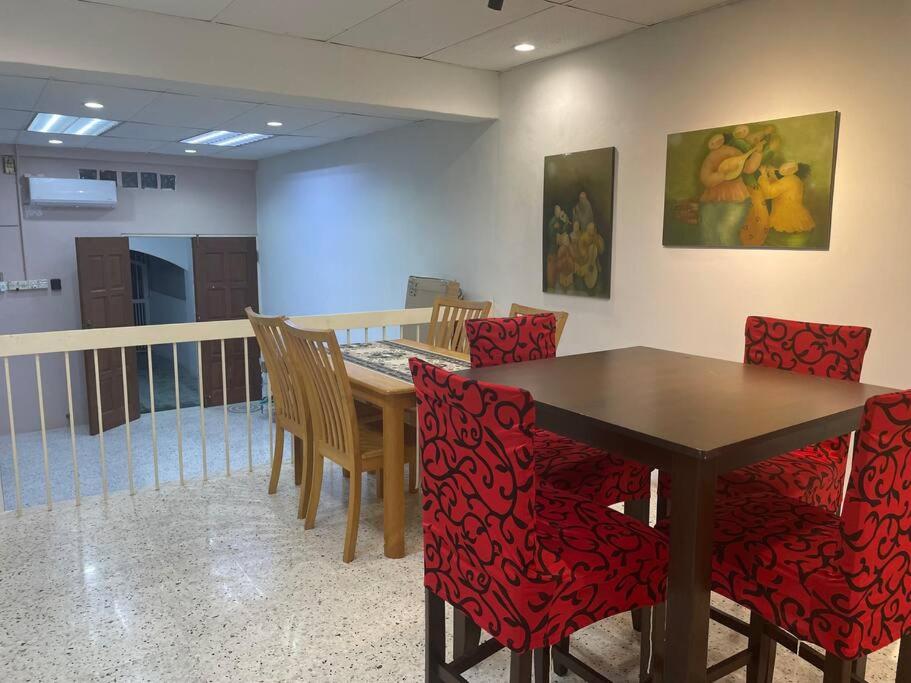 a dining room with a table and red chairs at Greenlane 4-bedroom landed home (12 pax) in Gelugor
