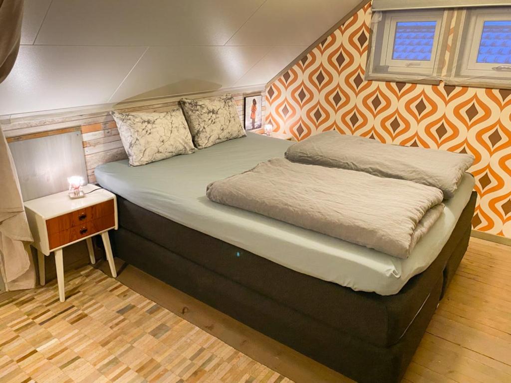 uma cama grande num pequeno quarto com uma mesa lateral em Nice little house right by the sea, stunning view! em Renså