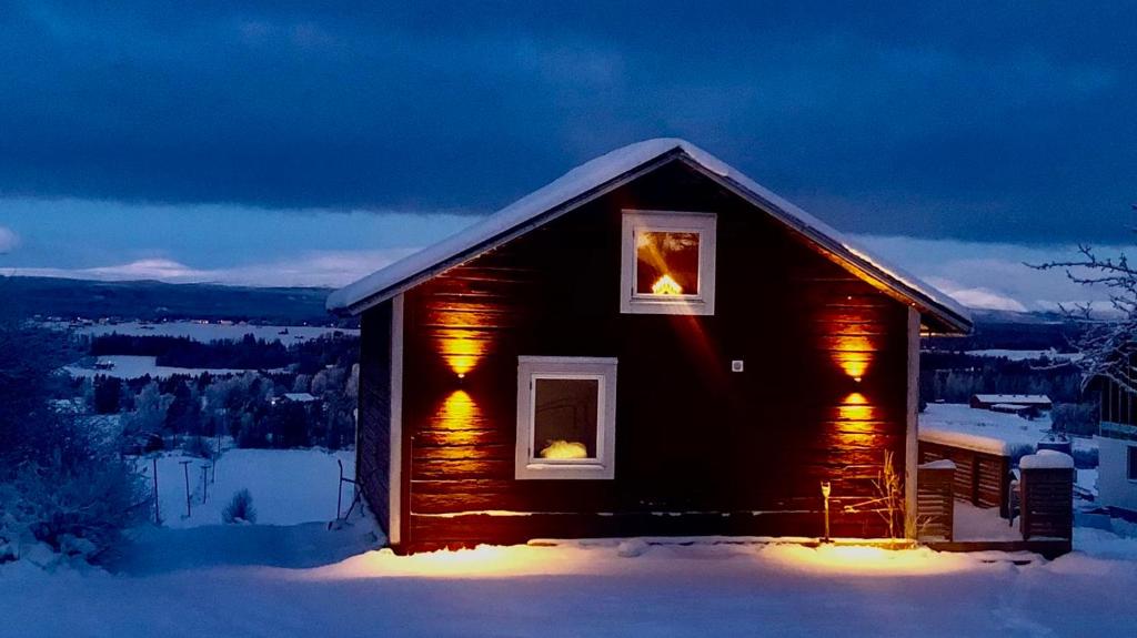 OvikenにあるTimmerstuga i Centrala Ovikenの夜の雪の小さな丸太小屋