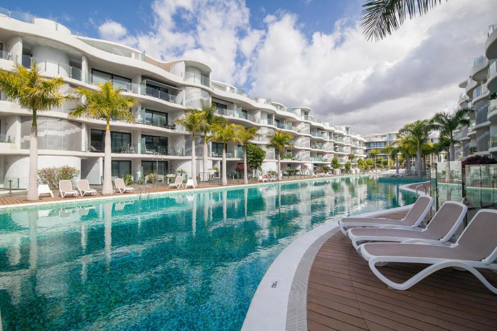 a swimming pool with lounge chairs next to a building at Luxury Avilla Las Olas in Palm-mar