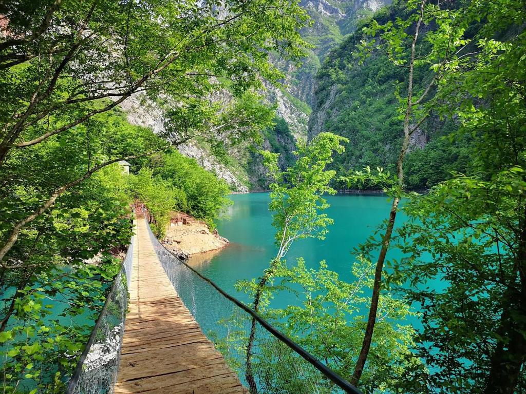 a wooden bridge over a lake in the forest at Riverside Komani Lake in Koman