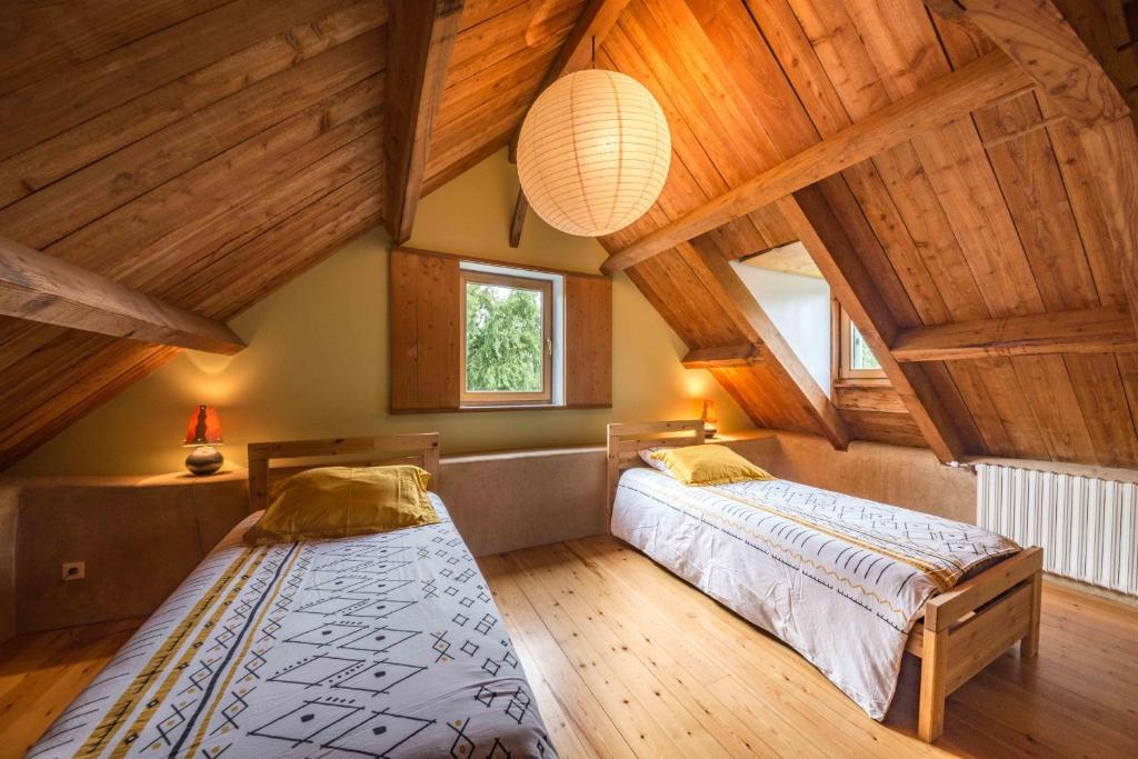 two beds in a room with wooden ceilings at MAISON YUKTI - Magnifique maison de charme proche plage in Lampaul-Ploudalmézeau