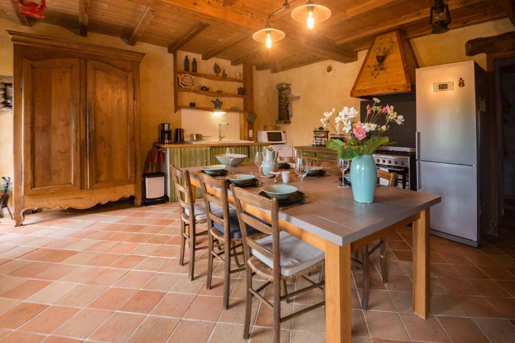 a kitchen with a table with chairs and a refrigerator at MAISON YUKTI - Magnifique maison de charme proche plage in Lampaul-Ploudalmézeau