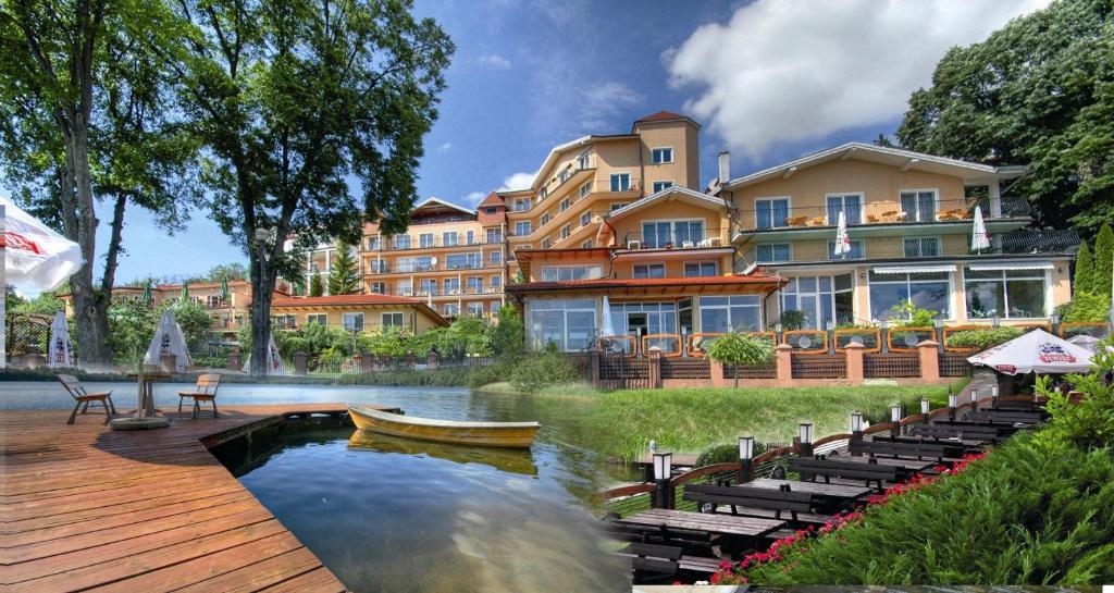 a resort with a boat in the water and a building at Panoramic-Oscar in Mrągowo