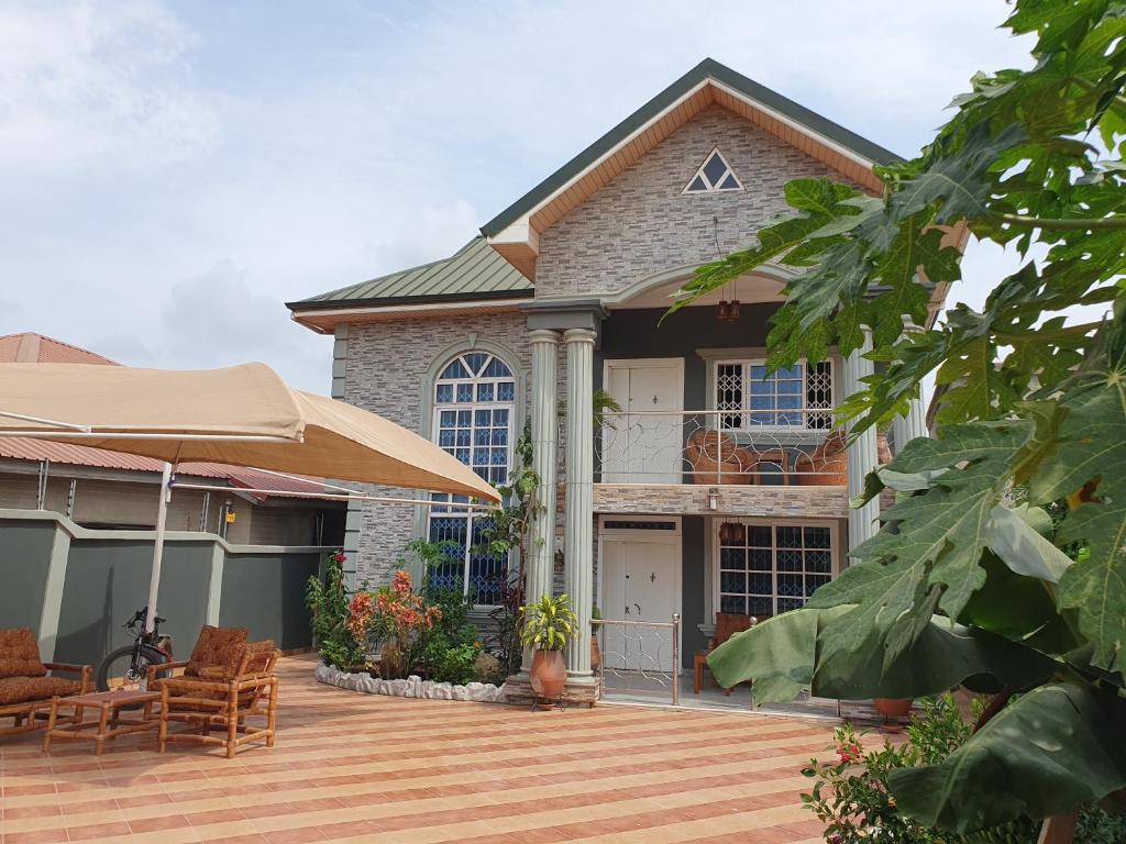 ein Haus mit einer Terrasse mit Stühlen und einem Sonnenschirm in der Unterkunft Villa Nelomoor in Kwabenyan