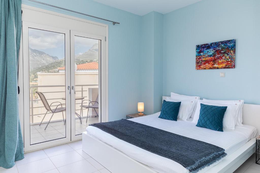 a white bedroom with a bed and a balcony at Villa Marcella in Plakias