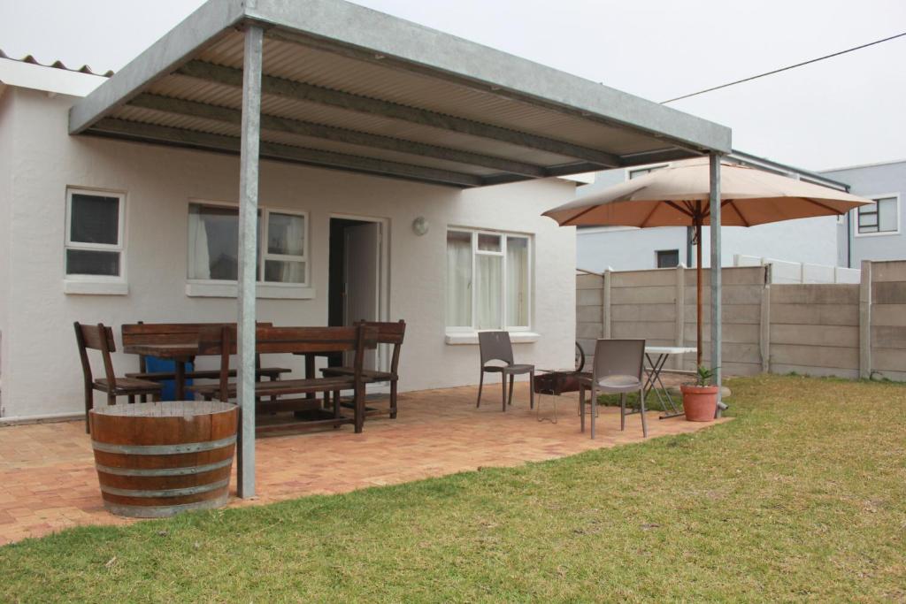 a patio with a table and chairs and an umbrella at Kusweg Suid 4 in Struisbaai