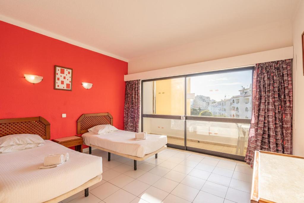 a room with two beds and a large window at Eirasol by Umbral in Albufeira