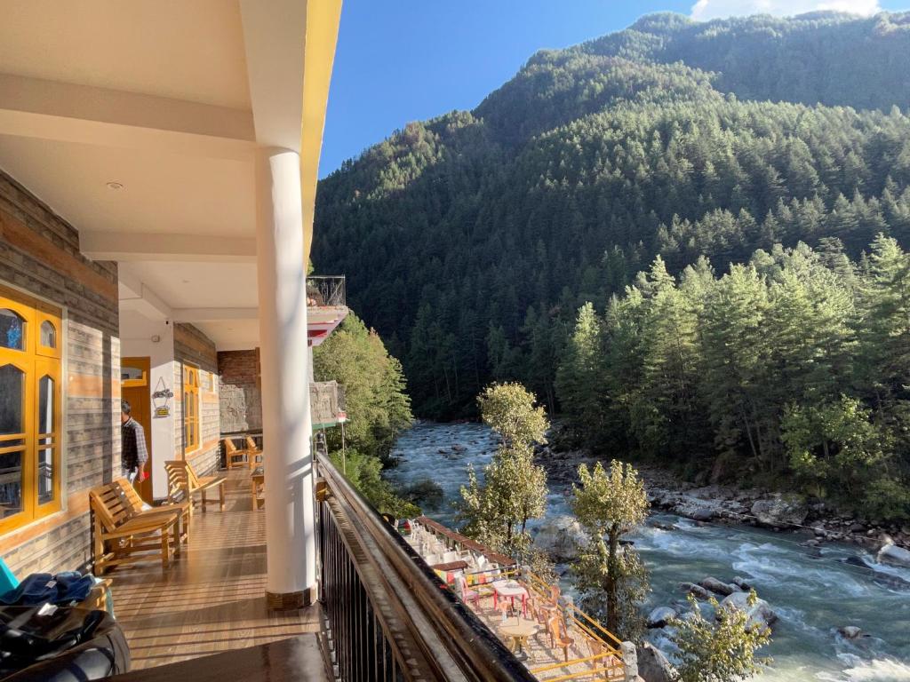 a balcony with a view of a river and mountains at Wabi Sabi Riverside Hostel in Kasol