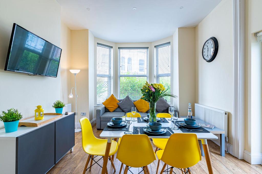 a dining room with a table and yellow chairs at Greyfriars in Clacton-on-Sea