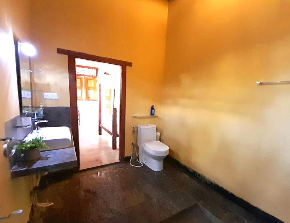 a bathroom with a toilet and a sink and a door at Angelica Villa in Bentota