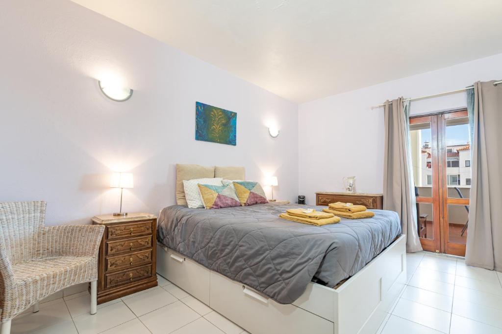 a bedroom with a bed and a chair and a window at Apartamento Stª Eulália Deluxe by Umbral in Albufeira
