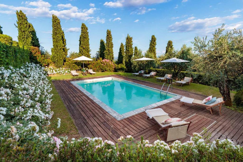 un patio trasero con piscina y terraza de madera en VILLA IL TINAIO Romantic Secluded Farmhouse with Private Pool, en Valgiano
