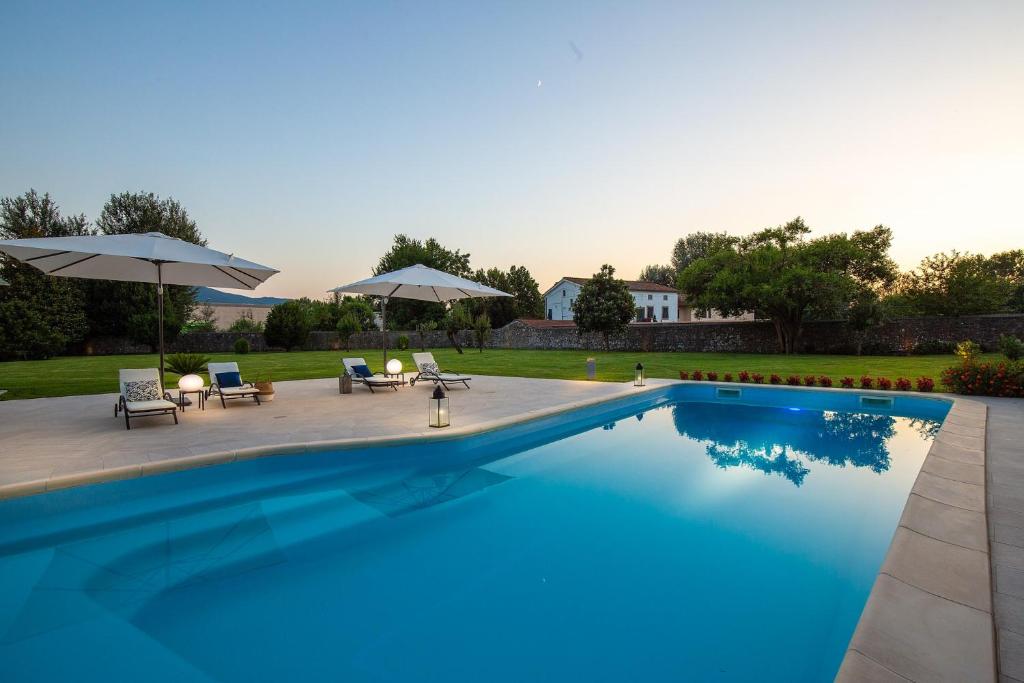 einen Pool mit Stühlen und Sonnenschirmen neben einem Hof in der Unterkunft Honeymoon Leonor Villa in Lucca