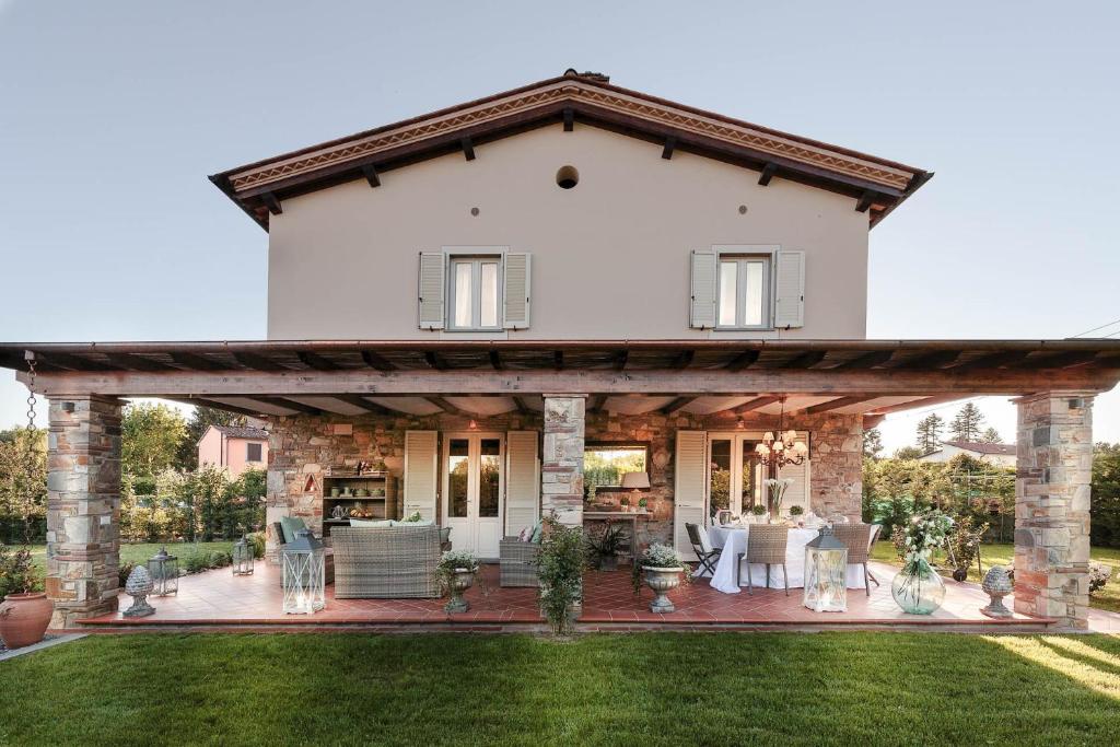 une grande maison blanche avec une grande pergola en bois dans l'établissement VILLA PEMOLA a Luxury Farmhouse with Garden and bikes in Lucca Town, à Parezzana