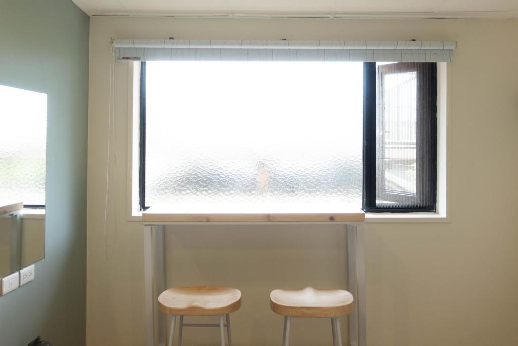 two stools sitting under a window in a room at Cen Pin B&amp;B in Jiufen