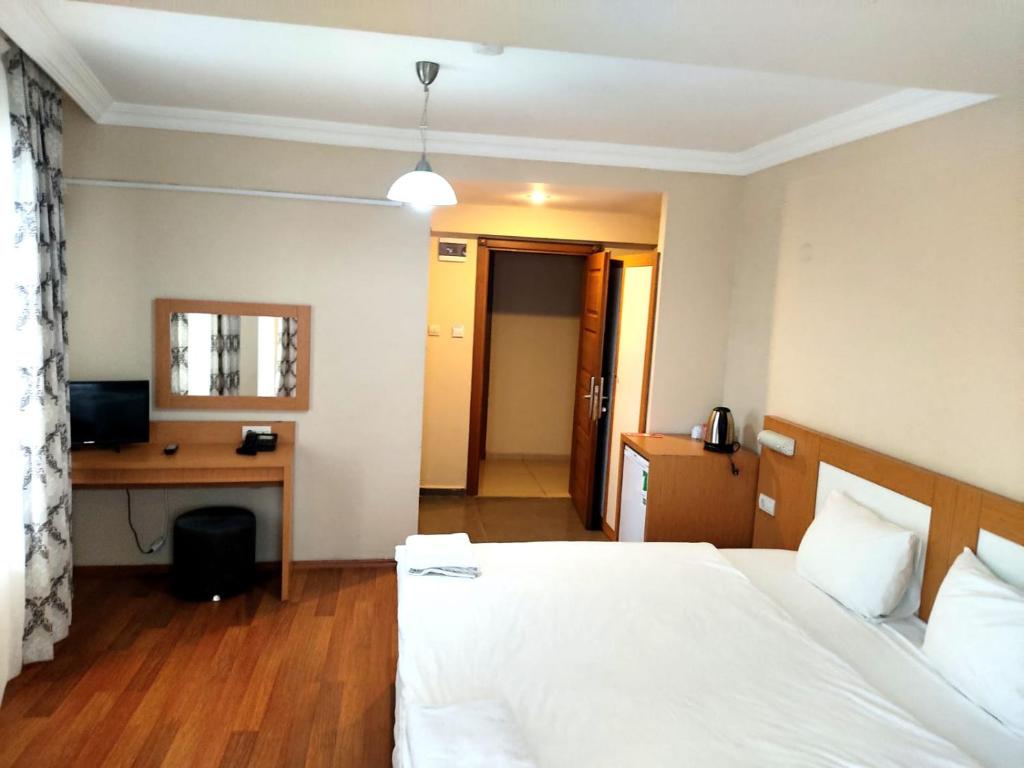1 dormitorio con cama blanca y escritorio en MD CITY HOTEL, en Canakkale