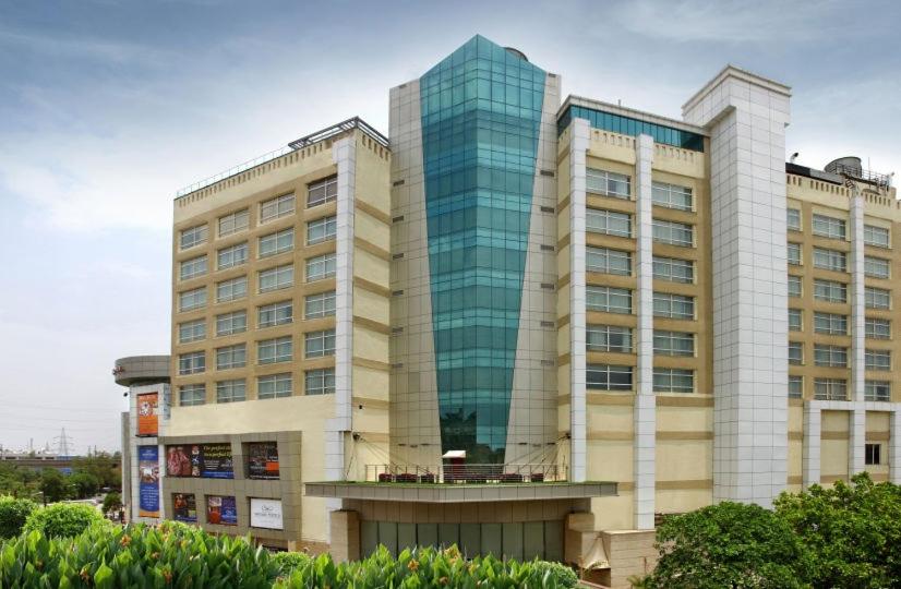 a large building with glass windows in front of it at Mahagun Sarovar Portico Suites in Ghaziabad