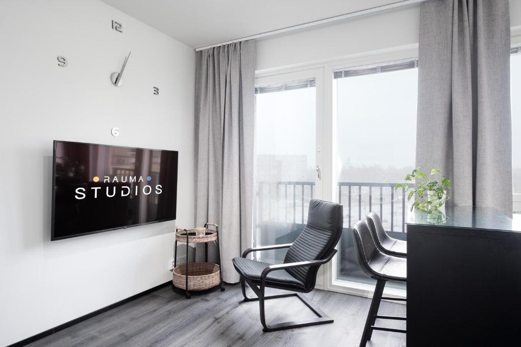 a living room with chairs and a tv on a wall at Rauma City Center Studios in Rauma