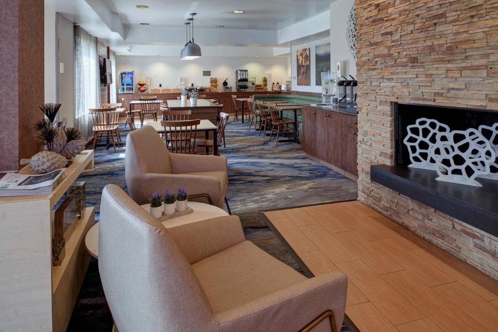 a lobby with chairs and a fireplace and a restaurant at Fairfield Inn by Marriott Kalamazoo West in Kalamazoo
